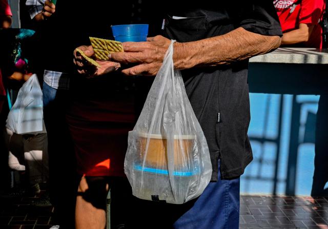 An elderly worshipper carries a bag after receiving a free meal at the Nazareth Baptist Church in the neighborhood of La Vibora, in Havana, on April 14, 2026. Dozens of people, mainly elderly and low income persons, come to this church to receive free medicines they cannot find in pharmacies or hospitals, reflecting the social role churches are playing in a Cuba in crisis. (Photo by ADALBERTO ROQUE / AFP)