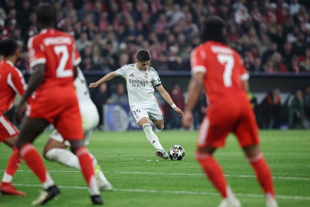 Real Madrid's Turkish midfielder #15 Arda Guler shoots and scores the 1-2 goal from a free kick during the UEFA Champions League quarter-final second leg football match between FC Bayern Munich and Real Madrid in Munich, southern Germany, on April 15, 2026. (Photo by Alexandra BEIER / AFP)