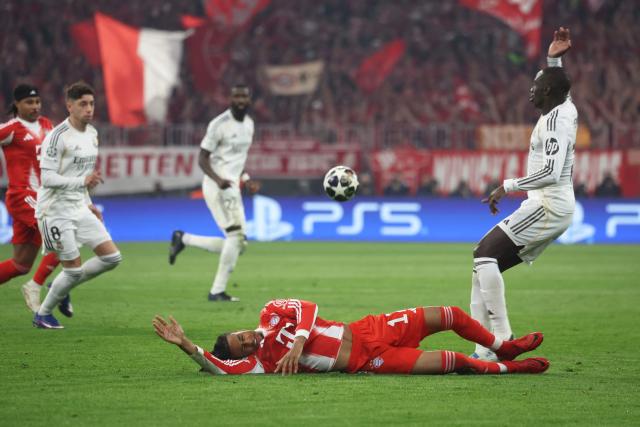 Bayern Munich's French midfielder #17 Michael Olise (C, bottom) reacts on the ground as Real Madrid's French defender #23 Ferland Mendy (R) gestures during the UEFA Champions League quarter-final second leg football match between FC Bayern Munich and Real Madrid in Munich, southern Germany, on April 15, 2026. (Photo by Karl-Josef HILDENBRAND / AFP)