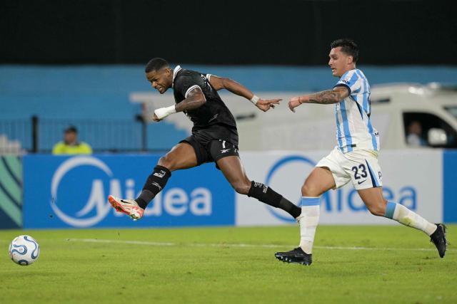 Botafogo's forward #07 Junior Santos kicks the ball and scores his team's second goal past Racing's defender #23 Nazareno Colombo during the Copa Sudamericana group stage football match between Argentina's Racing Club and Brazil's Botafogo at the Presidente Peron 'El Cilindro' stadium, in Avellaneda, Buenos Aires province, Argentina on April 15, 2026. (Photo by JUAN MABROMATA / AFP)