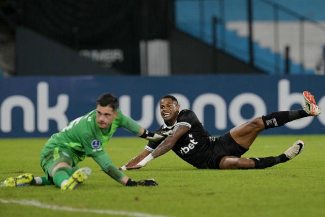Botafogo's forward #07 Junior Santos (R) reacts after scoring his team's second goal past Racing's goalkeeper #25 Facundo Cambeses during the Copa Sudamericana group stage football match between Argentina's Racing Club and Brazil's Botafogo at the Presidente Peron 'El Cilindro' stadium, in Avellaneda, Buenos Aires province, Argentina on April 15, 2026. (Photo by JUAN MABROMATA / AFP)