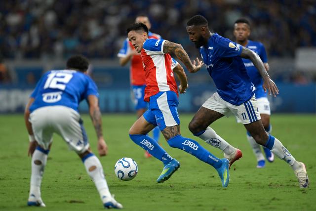 Universidad Catolica's Argentine midfielder #10 Matias Palavecino (C) and Cruzeiro's midfielder #11 Gerson fight for the ball during the Copa Libertadores group stage football match between Brazil's Cruzeiro and Chile's Universidad Catolica at the Mineirao stadium in Belo Horizonte, state of Minas Gerais, Brazil, on April 15, 2026. (Photo by DOUGLAS MAGNO / AFP)