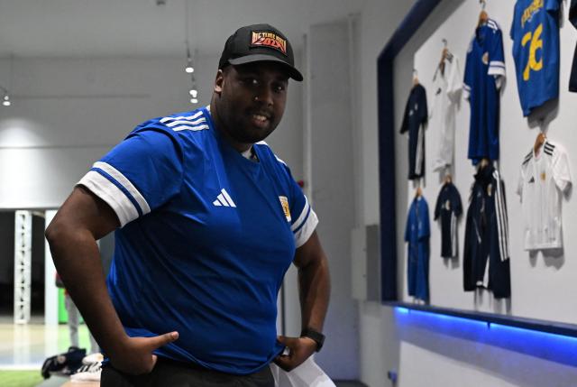 A man tries on a jersey of the Curacao national football team at the official fan store in Willemstad, Curacao, in the Dutch Caribbean, on April 8, 2026. Small island, big dreams. The poster of Curacao’s national football team hangs at the entrance of Marchena, a working-class neighborhood of Willemstad, the capital of the smallest territory ever to qualify for a World Cup. (Photo by Raul ARBOLEDA / AFP)