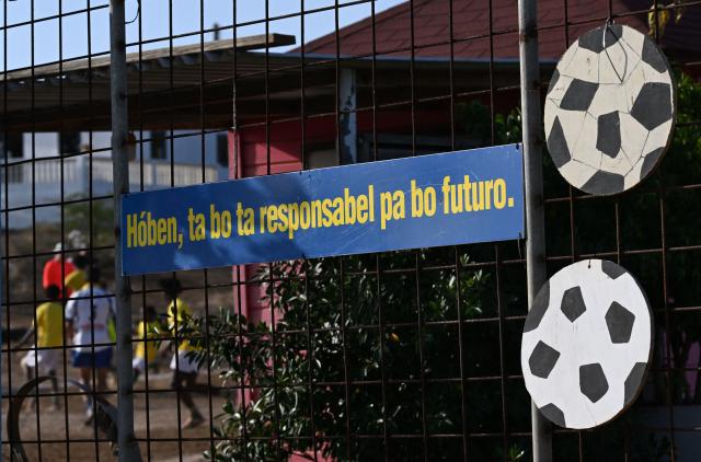 View of a sign reading "Young people are responsible for their future" during a training session of the Bicentini Foundation football school in the Fuik neighborhood, east of Willemstad, in the Dutch Caribbean, on April 11, 2026. Small island, big dreams. The poster of Curacao’s national football team hangs at the entrance of Marchena, a working-class neighborhood of Willemstad, the capital of the smallest territory ever to qualify for a World Cup. (Photo by Raul ARBOLEDA / AFP)