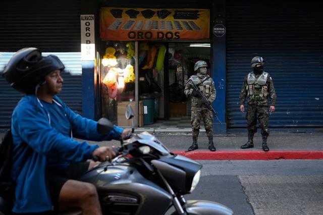 Guatemala's soldiers stand guard on a street of Guatemala City on April 15, 2026. Military forces put in place the 'Sentinel Plan' which seeks to provide security in the metropolitan area to curb extortion and neutralize gang operations. (Photo by JOHAN ORDONEZ / AFP)