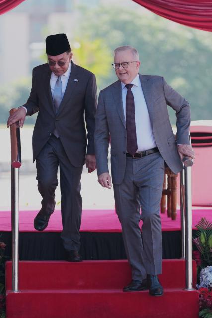Australia's Prime Minister Anthony Albanese (R) walks with Malaysia's Prime Minister Anwar Ibrahim to meet cabinet members after an official welcoming ceremony at the Federal Government office "Putra Perdana" in Putrajaya on April 16, 2026. (Photo by Vincent Thian / POOL / AFP)