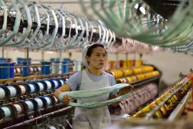 A woman works on a silk production line at Anhui Jingjiu Silk Company in Fuyang City, in China's eastern Anhui province on April 16, 2026. (Photo by CN-STR / AFP) / China OUT