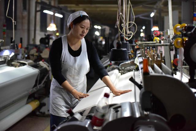 A woman works on a silk production line at Anhui Jingjiu Silk Company in Fuyang City, in China's eastern Anhui province on April 16, 2026. (Photo by CN-STR / AFP) / China OUT