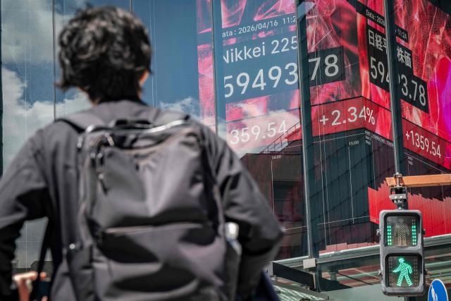 A man looks at an electronic quotation board displaying the Nikkei Stock Average on the Tokyo Stock Exchange in Tokyo on April 16, 2026. Japan's Nikkei index surged more than two percent on April 16 to hit a fresh record on optimism about an accord in the US-Iran conflict. (Photo by Yuichi YAMAZAKI / AFP)