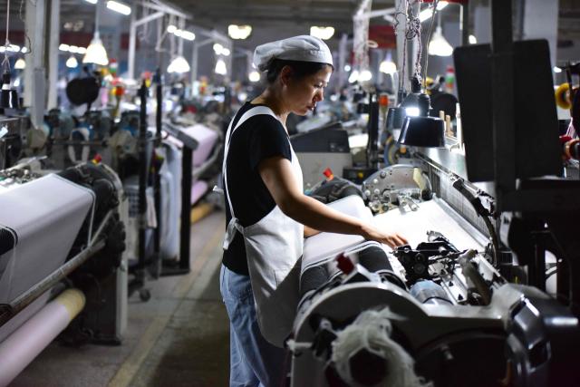 A woman works on a silk production line at Anhui Jingjiu Silk Company in Fuyang City, in China's eastern Anhui province on April 16, 2026. (Photo by CN-STR / AFP) / China OUT