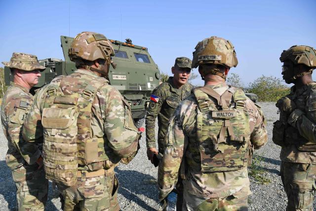 US soldiers (in brown) talk to a Philippine soldier (back C) prior to a live fire exercise of their High Mobility Artillery Rocket System (HIMARS) during the joint exercise between the Philippines and the US at Fort Magsaysay, in the Philippines' Nueva Ecija province north of Manila on April 16, 2026. (Photo by Ted ALJIBE / AFP)