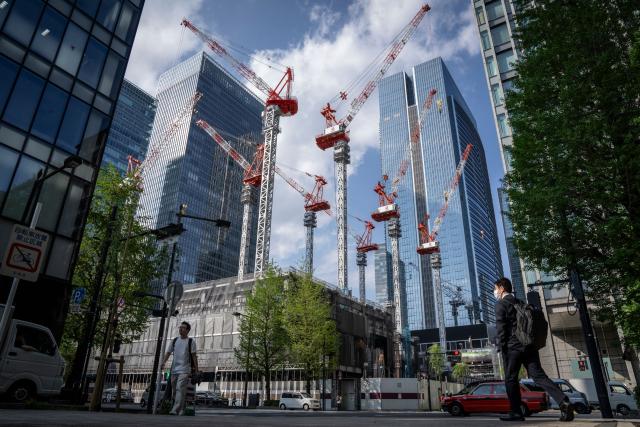 People walk past a construction site in Tokyo on April 16, 2026. (Photo by Yuichi YAMAZAKI / AFP)