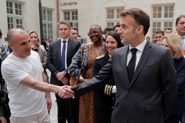 France's President Emmanuel Macron (R) shakes hands with French rapper Virus during his visit to the International City of French Language (Cite Internationale de la Langue Francaise) to promote 'disconnecting' and 'reading' as alternatives to screens as part of his fight to ban social networks for the youngest in the castle of Villers-Cotterets, northern France on April 16, 2026. In response to the explosion in screen time among 6- to 17-year-olds and the impact of algorithms on our children, Emmanuel Macron has pledged to ban social media for those under 15. (Photo by Ludovic MARIN / POOL / AFP)