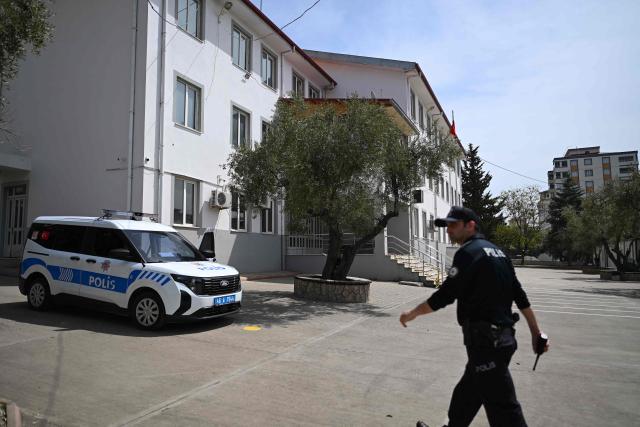 A Police officer stands guard near the Ayser Calik college ahead of the funerals for nine victims killed in a school shooting by a 14-year-old, an attack that has sent shockwaves across the country, with authorities saying the suspect had referenced a US mass killer in a WhatsApp profile image, in the southern province of Kahramanmaras on April 16, 2026. The funerals take place for eight children aged 10 and 11 and a 55-year-old teacher. (Photo by YASIN AKGUL / AFP)