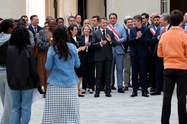 France's President Emmanuel Macron (C) applauds middle school students during his visit to the International City of French Language (Cite Internationale de la Langue Francaise) to promote 'disconnecting' and 'reading' as alternatives to screens as part of his fight to ban social networks for the youngest in the castle of Villers-Cotterets, northern France on April 16, 2026. In response to the explosion in screen time among 6- to 17-year-olds and the impact of algorithms on our children, Emmanuel Macron has pledged to ban social media for those under 15. (Photo by Ludovic MARIN / POOL / AFP)