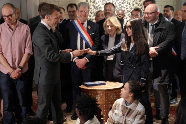 France's President Emmanuel Macron (L) meets with students from a comic book workshop during a visit to the International City of French Language (Cite Internationale de la Langue Francaise) to promote 'disconnecting' and 'reading' as alternatives to screens as part of his fight to ban social networks for the youngest in the castle of Villers-Cotterets, northern France on April 16, 2026. In response to the explosion in screen time among 6- to 17-year-olds and the impact of algorithms on our children, Emmanuel Macron has pledged to ban social media for those under 15. (Photo by Ludovic MARIN / POOL / AFP)