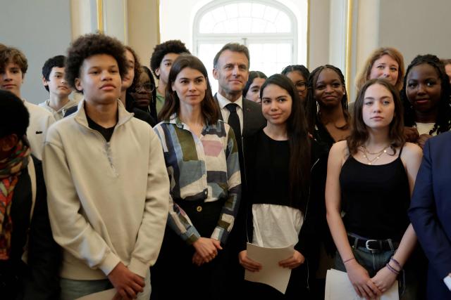 France's President Emmanuel Macron (C) poses with middle school students after a theater workshop during his visit to the International City of French Language (Cite Internationale de la Langue Francaise) to promote 'disconnecting' and 'reading' as alternatives to screens as part of his fight to ban social networks for the youngest in the castle of Villers-Cotterets, northern France on April 16, 2026. In response to the explosion in screen time among 6- to 17-year-olds and the impact of algorithms on our children, Emmanuel Macron has pledged to ban social media for those under 15. (Photo by Ludovic MARIN / POOL / AFP)
