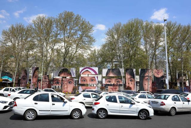 Cars drive past the portraits of children killed in a deadly strike on a children’s school in the southern city of Minab on the first day of the war that killed at least 165 people, most of them children, at the Tajrish Square in Tehran on April 16, 2026. The military adviser to Iran's supreme leader Mojtaba Khamenei on April 15 warned that Iran would sink American ships in the Strait of Hormuz if the United States decided to "police" the key shipping bottleneck. (Photo by AFP) / 