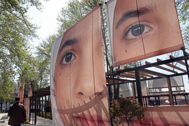 A man walks past the portraits of children killed in a deadly strike on a children’s school in the southern city of Minab on the first day of the war that killed at least 165 people, most of them children, at the Tajrish Square in Tehran on April 16, 2026. The military adviser to Iran's supreme leader Mojtaba Khamenei on April 15 warned that Iran would sink American ships in the Strait of Hormuz if the United States decided to "police" the key shipping bottleneck. (Photo by AFP) / 