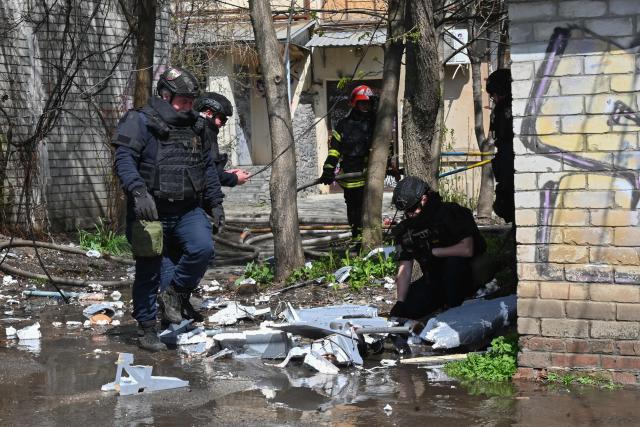 Ukrainian law enforcement officers inspect fragments of a drone at the site of an air attack in Kharkiv on April 16, 2026, amid the Russian invasion of Ukraine. A massive Russian drone and missile barrage killed at least 16 people in cities across Ukraine, more than four years into the war with peace talks stalled, Ukrainian officials said on April 16, 2026. (Photo by SERGEY BOBOK / AFP)