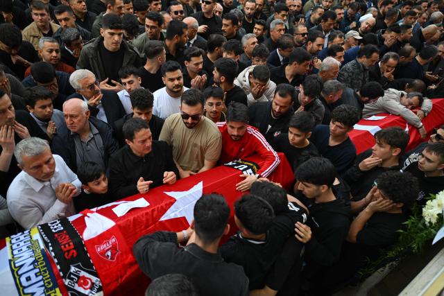 Family members and mourners stand next to the coffin of 10-year-old Bayram Nabi ?i?ik as they dattend the funerals for nine victims killed in a school shooting by a 14-year-old, an attack that has sent shockwaves across the country, with authorities saying the suspect had referenced a US mass killer in a WhatsApp profile image, in the southern province of Kahramanmaras on April 16, 2026. The funerals take place for eight children aged 10 and 11 and a 55-year-old teacher. (Photo by YASIN AKGUL / AFP)