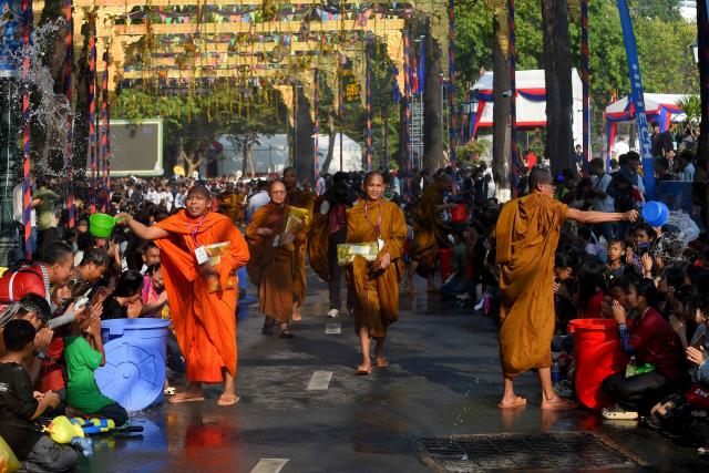 Cambodian Buddhist monks throw water on people during celebrations for the Khmer New Year, known as Nokor Sankranta, in Phnom Penh on April 16, 2026. (Photo by TANG CHHIN Sothy / AFP)
