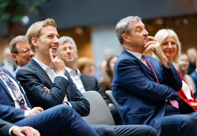 Munich's mayor Dominik Krause (L) and Bavaria's State Premier Markus Soeder Offices attend a ceremony of the opening of retail company Amazon Germany's new headquarter building on April 16, 2026 in Munich. Amazon has had its German headquarters in Bavaria in various offices for nearly 30 years and employs over 6,000 people there. (Photo by AFP)