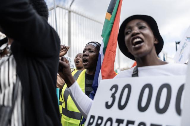 Protesters who are pro-democracy for Iran wave the South African national flag and hold placards while chanting during a protest in front of the US Consulate in Sandton, on April 16, 2026. (Photo by ILARIA FINIZIO / AFP)