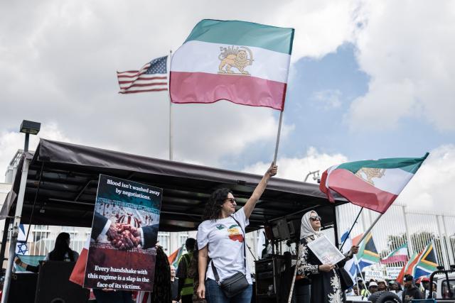 Iranian pro-democracy activists wave the pre-1979 Iranian national flag during a protest in front of the US Consulate in Sandton, on April 16, 2026. (Photo by ILARIA FINIZIO / AFP)