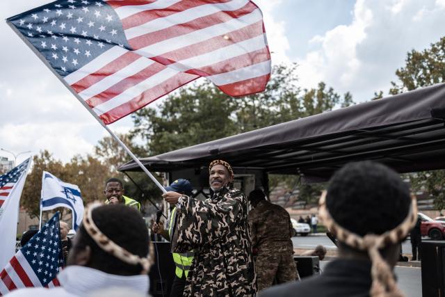 Leader of Shembe Nazareth Baptist Church, Bishop Phakama Shembe (C), waves the US flag during a protest in front of the US Consulate in Sandton, on April 16, 2026. (Photo by ILARIA FINIZIO / AFP)