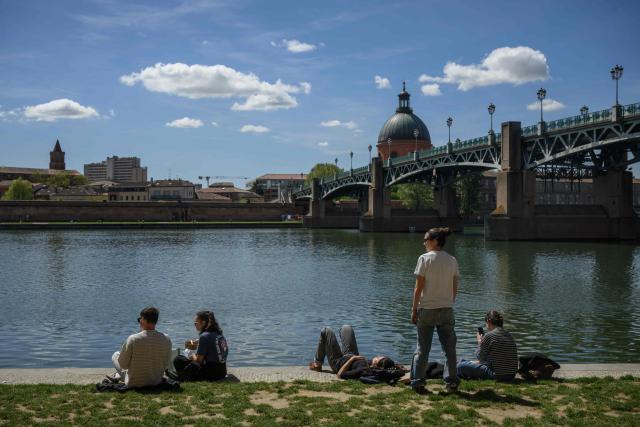 People sit on the banks of the Garonne river with a view of the Chapelle Saint-Joseph de la Grave in Toulouse on April 16, 2026. (Photo by Ed JONES / AFP)