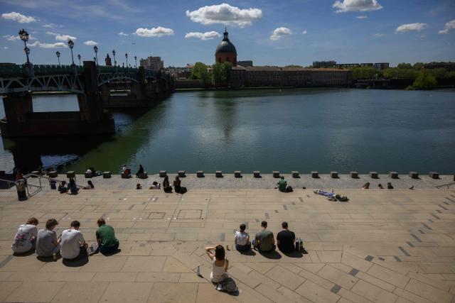 People sit on the banks of the Garonne river with a view of the Chapelle Saint-Joseph de la Grave in Toulouse, southern France, on April 16, 2026. (Photo by Ed JONES / AFP)