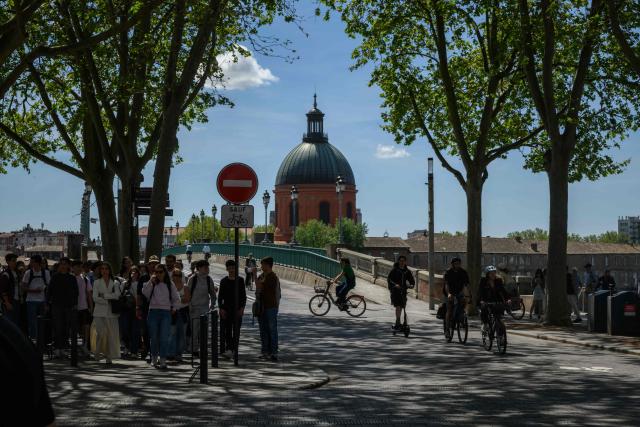 A general view shows pedestrians and cyclists before the Garonne river with a view of the Chapelle Saint-Joseph de la Grave in Toulouse, southern France, on April 16, 2026. (Photo by Ed JONES / AFP)