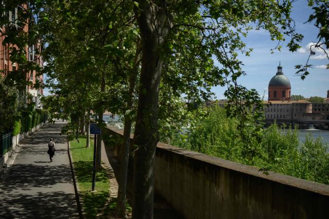 A woman walks beside the Garonne river with a view of the Chapelle Saint-Joseph de la Grave in Toulouse, southern France, on April 16, 2026. (Photo by Ed JONES / AFP)