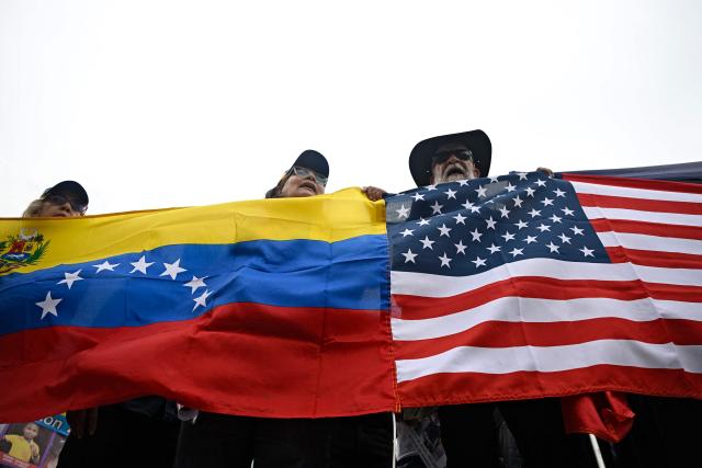 People hold Venezuelan and US flags during a protest at the Alfredo Sadel square in Caracas on April 16, 2026, to demand a political transition in Venezuela. (Photo by Federico PARRA / AFP)