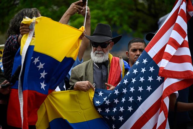 People hold Venezuelan and US flags during a protest at the Alfredo Sadel square in Caracas on April 16, 2026, to demand a political transition in Venezuela. (Photo by Federico PARRA / AFP)
