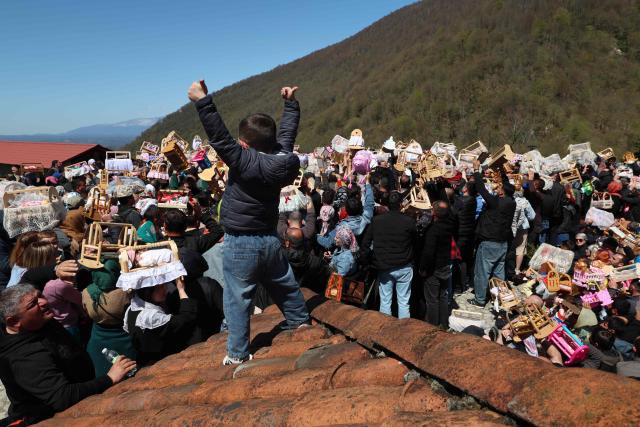 Pilgrims, including childless couples, with toy cradles participate in the Tsachkhuroba pilgrimage to the hill-sit Archangel monastery to pray God and ask for mercy and for a child, in the village of Tsachkhuri on April 16, 2026. Thousands joined the 3 km uphill monastery procession in an annual fertility pilgrimage, happening on Thursday of the week following Orthodox Easter. (Photo by Giorgi ARJEVANIDZE / AFP)
