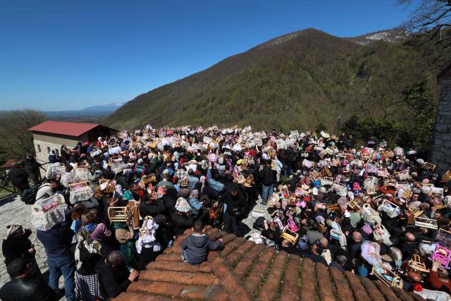 Pilgrims, including childless couples, with toy cradles participate in the Tsachkhuroba pilgrimage to the hill-sit Archangel monastery to pray God and ask for mercy and for a child, in the village of Tsachkhuri on April 16, 2026. Thousands joined the 3 km uphill monastery procession in an annual fertility pilgrimage, happening on Thursday of the week following Orthodox Easter. (Photo by Giorgi ARJEVANIDZE / AFP)