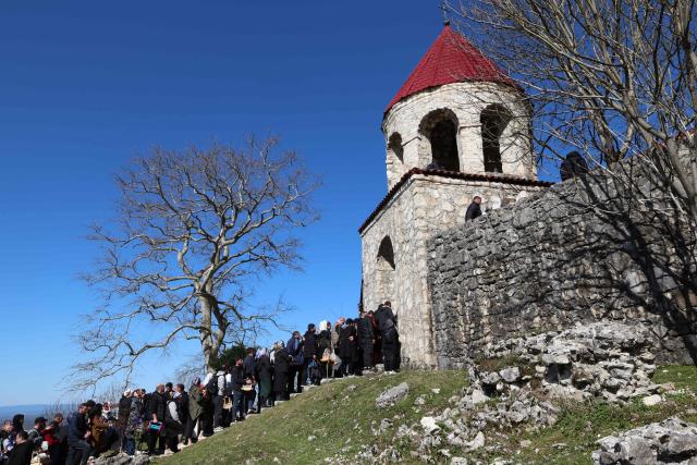 Pilgrims, including childless couples, with toy cradles participate in the Tsachkhuroba pilgrimage to the hill-sit Archangel monastery to pray God and ask for mercy and for a child, in the village of Tsachkhuri on April 16, 2026. Thousands joined the 3 km uphill monastery procession in an annual fertility pilgrimage, happening on Thursday of the week following Orthodox Easter. (Photo by Giorgi ARJEVANIDZE / AFP)