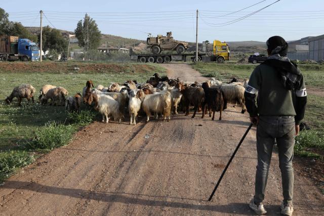 A Syrian shepherd looks on as a convoy of US military equipment is transported along the DamascusAmman highway toward the southwestern city of Daraa, near Damascus, following the completion of the US withdrawal from their bases on April 16, 2026. Syria said on April 16, it had taken control of all military bases hosting US troops who were deployed in the country for years leading an international coalition against the Islamic State (IS) group. In recent months, Syria's new Islamist government has expanded its control to parts of the country's northeast that were previously held by US-allied Kurdish forces, while the government has also formally joined the international anti-IS coalition. (Photo by Bakr ALkasem / AFP)