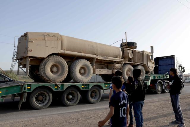 Syrian youth look on as a convoy of US military equipment is transported along the DamascusAmman highway toward the southwestern city of Daraa, following the completion of the US withdrawal from their bases, as it travels near the capital Damascus on April 16, 2026. Syria said on April 16, it had taken control of all military bases hosting US troops who were deployed in the country for years leading an international coalition against the Islamic State (IS) group. In recent months, Syria's new Islamist government has expanded its control to parts of the country's northeast that were previously held by US-allied Kurdish forces, while the government has also formally joined the international anti-IS coalition. (Photo by Bakr ALkasem / AFP)