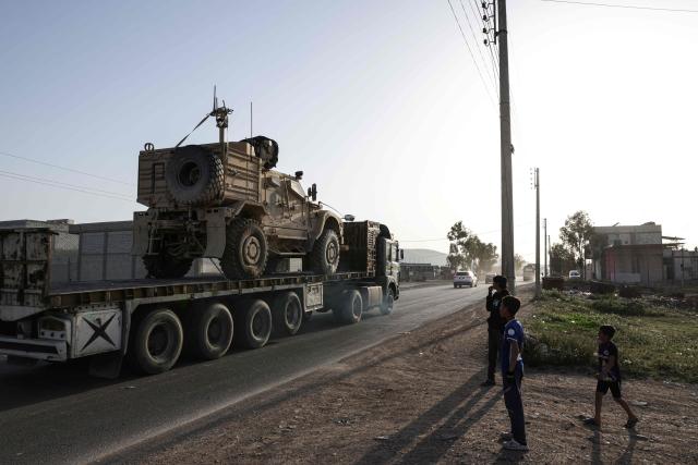 Syrian youth look on as a convoy of US military equipment is transported along the DamascusAmman highway toward the southwestern city of Daraa, following the completion of the US withdrawal from their bases, as it travels near the capital Damascus on April 16, 2026. Syria said on April 16, it had taken control of all military bases hosting US troops who were deployed in the country for years leading an international coalition against the Islamic State (IS) group. In recent months, Syria's new Islamist government has expanded its control to parts of the country's northeast that were previously held by US-allied Kurdish forces, while the government has also formally joined the international anti-IS coalition. (Photo by Bakr ALkasem / AFP)