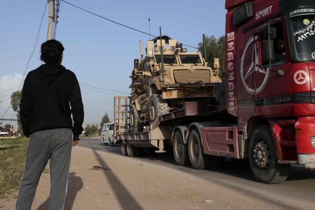 A Syrian youth watches a convoy of US military equipment being transported along the DamascusAmman highway toward the southwestern city of Daraa, following the completion of the US withdrawal from their bases, as it travels near the capital Damascus on April 16, 2026. Syria said on April 16, it had taken control of all military bases hosting US troops who were deployed in the country for years leading an international coalition against the Islamic State (IS) group. In recent months, Syria's new Islamist government has expanded its control to parts of the country's northeast that were previously held by US-allied Kurdish forces, while the government has also formally joined the international anti-IS coalition. (Photo by Bakr ALkasem / AFP)