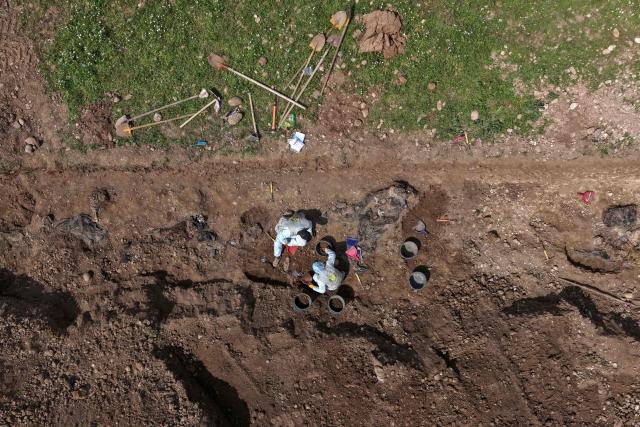 An aerial view shows forensic experts working as they open a mass grave containing what is believed to be the remains of dozens of people executed by Islamic State (IS) group during their entry into the the northern city of Mosul in 2014, capturing it from the Iraqi Army, in the Mushairifa area of Mosul on April 16, 2026. Work began on April 16, to recover remains from a mass grave dating back to the period when the Islamic State was in control of the city of Mosul in northern Iraq, an official told Agence France-Presse. Ahmed al-Asadi, head of the teams excavating mass graves in Iraq, told AFP, “Today, our teams began the process of exhuming” remains from a mass grave located in the al-Haramat area west of Mosul in Nineveh province. (Photo by Zaid AL-OBEIDI / AFP)