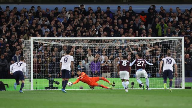 Bologna's Italian goalkeeper #13 Federico Ravaglia dives to save a penalty shot by Aston Villa's English midfielder #27 Morgan Rogers during the UEFA Europa League, quarter final second-leg football match between Aston Villa and Bologna at Villa Park in Birmingham, central England on April 16, 2026. (Photo by Darren Staples / AFP)
