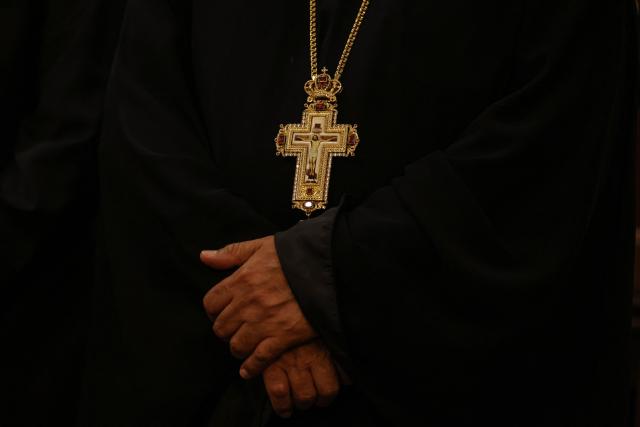 A Christian cleric joins worshippers as they attend a service at the Coptic Orthodox Patriarchate Church during a mass for "World Peace", where all Christian denominations gathered to pray for an end to the war in the Middle East, in Baghdad on April 16, 2026.  (Photo by AHMAD AL-RUBAYE / AFP)