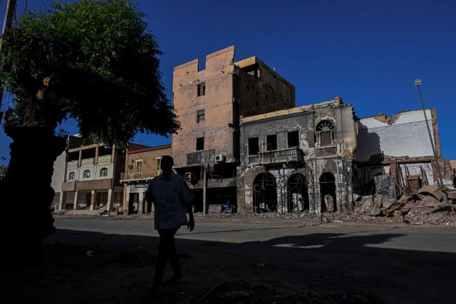 A Sudanese man walks past destroyed building in the capital Khartoum on April 16, 2026. Of the nearly four million people -- around half Khartoum's pre-war population -- who fled during the conflict, more than 1.8 million have returned over the past year. Yet fewer than 80,000 people have come back to central Khartoum, according to the United Nations. (Photo by Khaled DESOUKI / AFP)