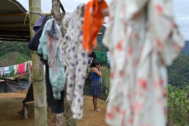 An Embera Chami Indigenous woman talks on a radiotelephone in Vereda Tuma Drua, in the unified Embera Chami Rio San Juan reservation, Pueblo Rico, Risaralda, Colombia, on April 9, 2026. In the coffee-growing mountains of the Risaralda department in western Colombia, ancestral territory of the Embera Chami and Katio peoples, genital mutilation affects hundreds of girls. (Photo by Diana SANCHEZ / AFP)