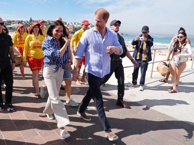 Britain's Prince Harry, Duke of Sussex, and his wife Meghan, the Duchess of Sussex, walk along Bondi Beach after meeting with volunteer first responders from Bondi Surf Bathers' Life Saving Club in Sydney on April 17, 2026. (Photo by Jonathan Brady / POOL / AFP)