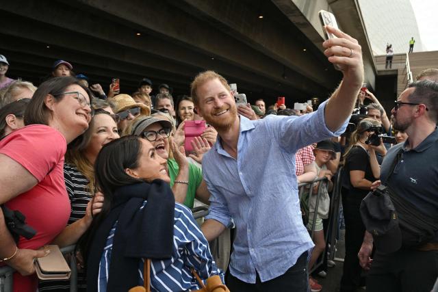 Britain’s Prince Harry, Duke of Sussex, and his wife Meghan, Duchess of Sussex, pose for selfies with members of the public beneath the steps of Australia’s iconic Sydney Opera House on April 17, 2026. (Photo by Saeed KHAN / AFP)